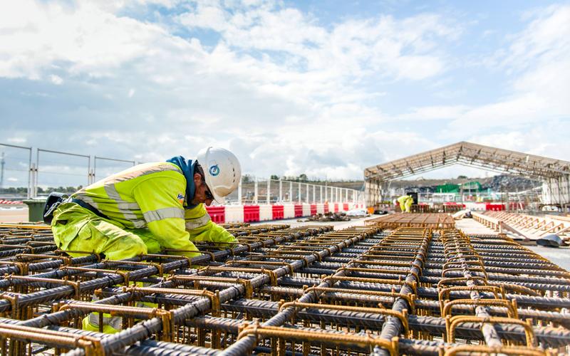 person in high visibility outdoor outfit inspecting steel foundations for construction