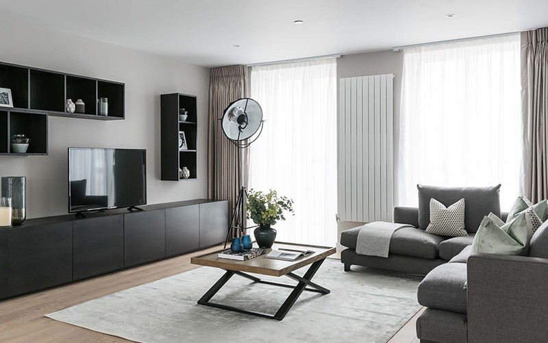 living room with tv and shelving near a black lamp and dark beige sofas