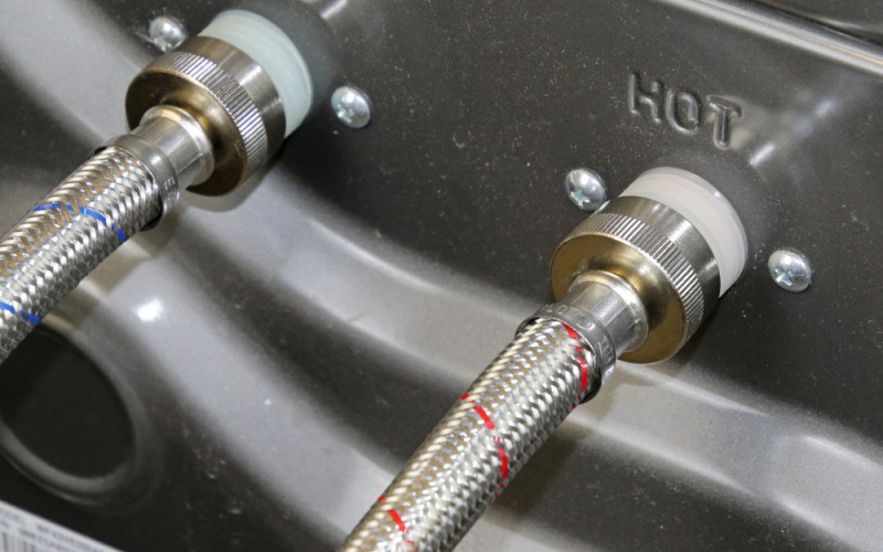 Close up of hot and cold washing machine connector hoses