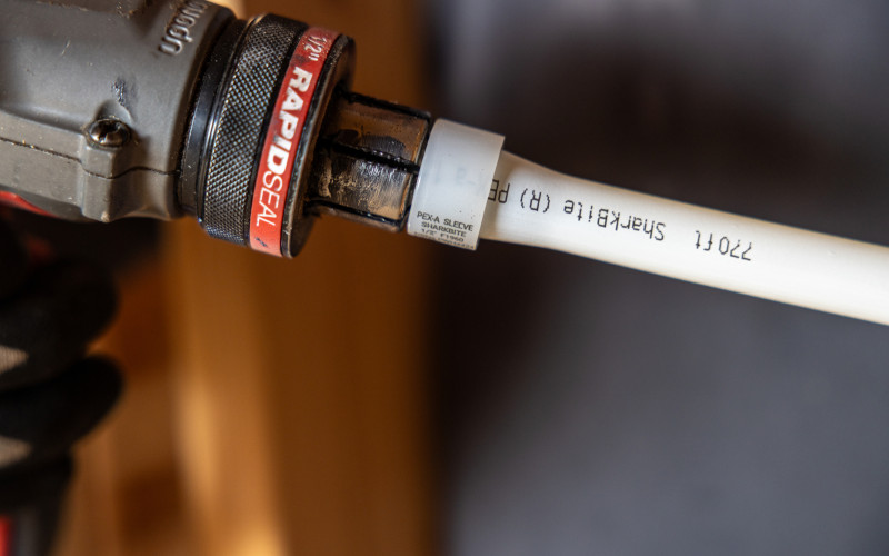 Close-up of a plumbing pipe connected with a SharkBite Expansion fitting during installation inside a residential construction project.