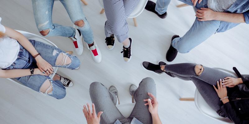 High angle of rehab specialist and rebellious teenagers sitting in the circle during meeting.