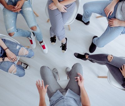 High angle of rehab specialist and rebellious teenagers sitting in the circle during meeting.